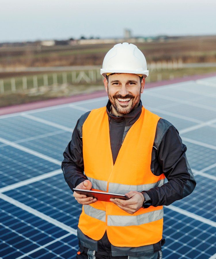 A solar installer with a tablet beside a panel array